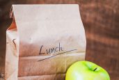 Brown bag lunch and green apple on canvas background and copy space