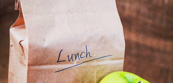 Brown bag lunch and green apple on canvas background and copy space